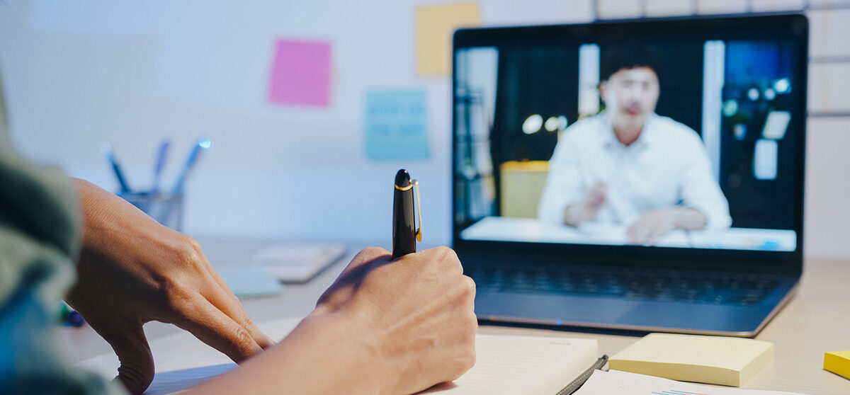 woman participating in a video call on her laptop with a male colleague.