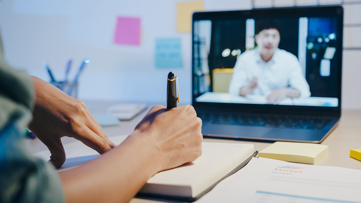 woman participating in a video call on her laptop with a male colleague.